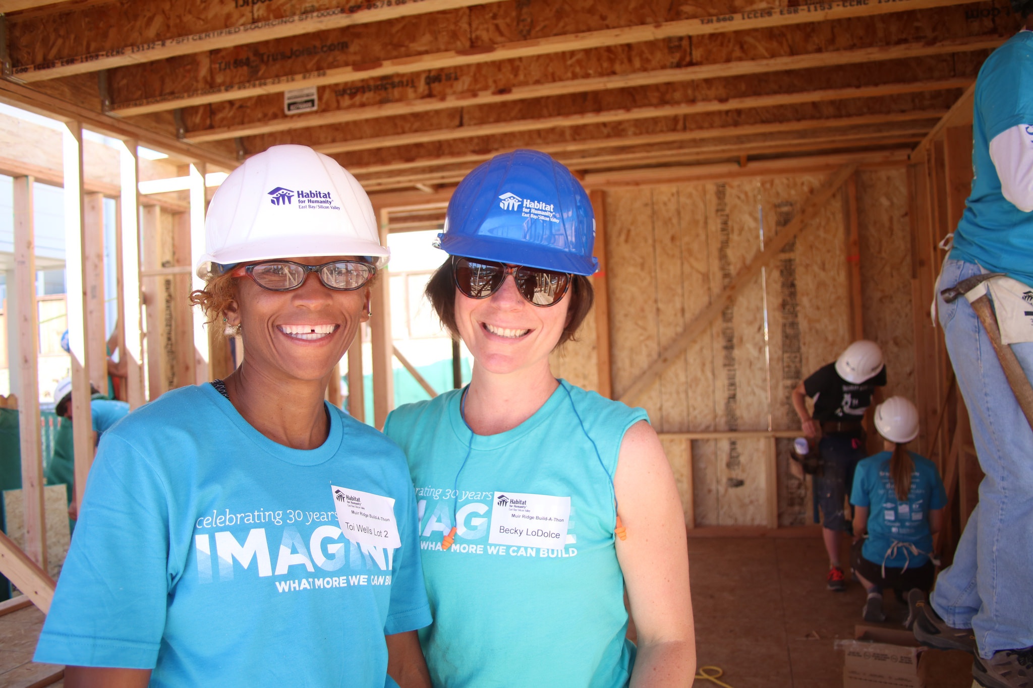 Two smiling Habitat volunteers with hard hats