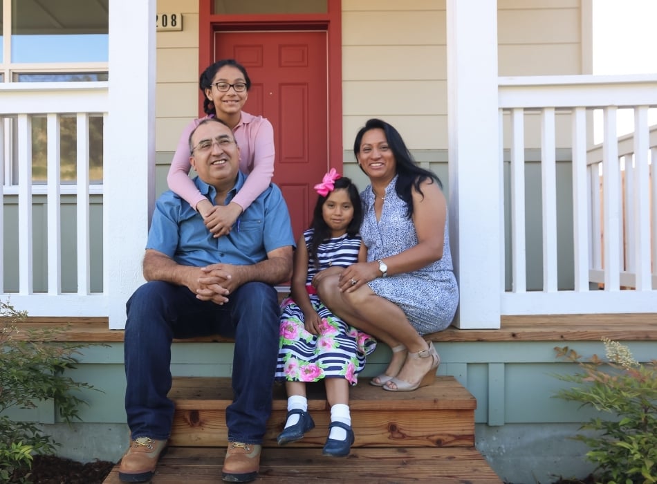 Family sitting on front porch of their new home
