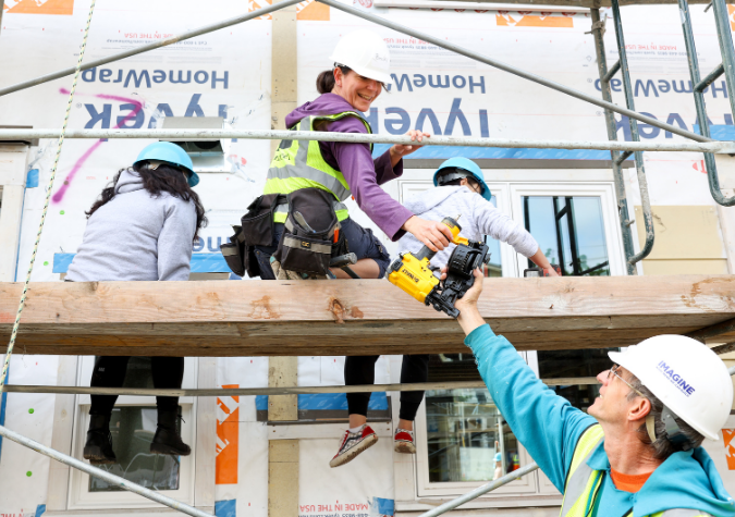 a volunteer handing another volunteer a tool