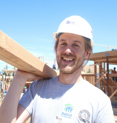 AmeriCorps volunteer carrying two by four piece of wood
