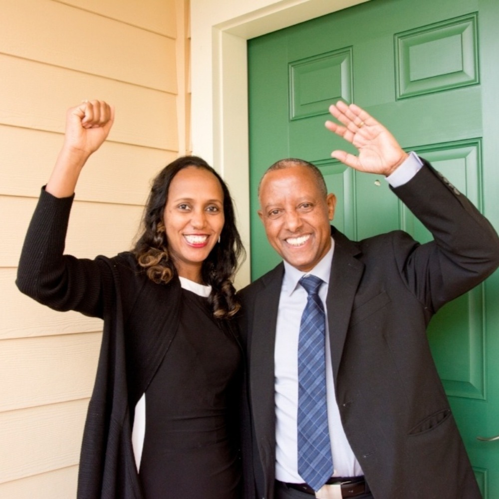 A husband and wife in front of their home