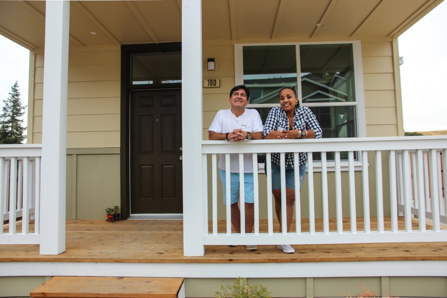 Couple standing on the front porch of their new home