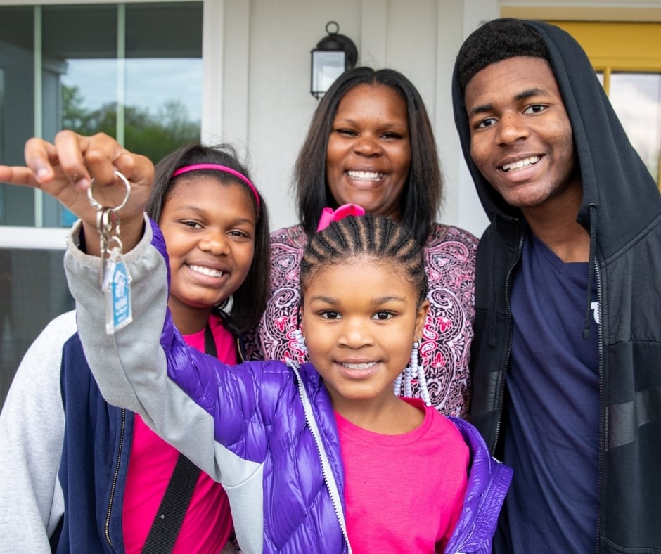 family holding up key in front of home